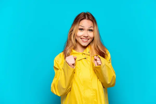 stock image Teenager girl wearing a rainproof coat over isolated blue background celebrating a victory in winner position