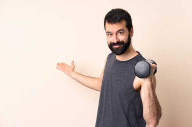 Beyaz sakallı spor adamı izole edilmiş arka planda ağırlık kaldırıyor. Gelmesi için ellerini yana açıyor.