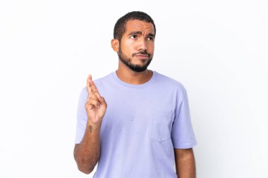 Young Ecuadorian man isolated on white background with fingers crossing and wishing the best