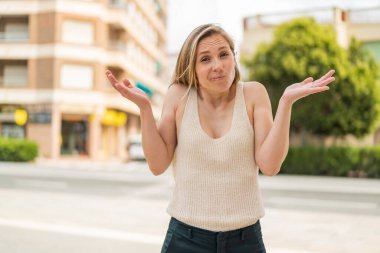 Açık havada genç sarışın bir kadın şüpheli hareketler yapıyor.