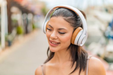 Açık havada müzik dinleyen genç ve güzel bir kadın.