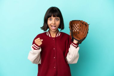 Beyzbol eldivenli genç melez kadın mavi arka planda izole edilmiş galibiyeti kutluyor.