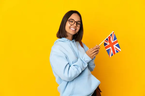 stock image Young latin woman holding an United Kingdom flag isolated on yellow background applauding