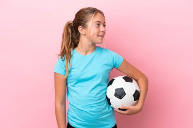 Pembe arka planda izole edilmiş küçük futbolcu kız.