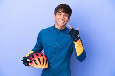 Mor arka planda izole edilmiş genç bir beyaz adam baş parmak hareketi yapıyor.