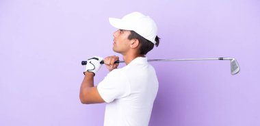 Mor arka planda golf oynayan beyaz bir genç.