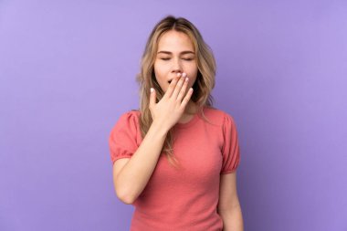 Mor arka planda izole edilmiş genç Rus kız esniyor.