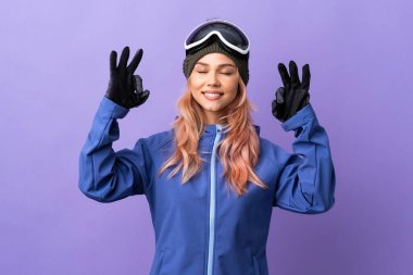 Kar kayağı gözlüklü genç kız Zen pozisyonunda mor arka planda.