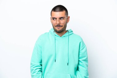 Beyaz arka planda izole edilmiş genç beyaz adam yukarı bakarken şüpheleri var.