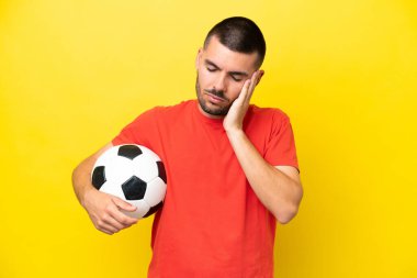 Futbol oynayan beyaz bir adam sarı arka planda izole edilmiş baş ağrısıyla.