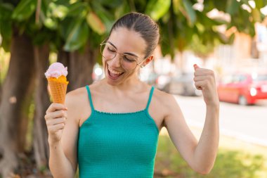 Açık havada kornet dondurmalı genç ve güzel bir kadın zaferi kutluyor.