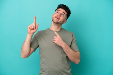 Mavi arka planda izole edilmiş genç beyaz adam işaret parmağıyla işaret etmek harika bir fikir.