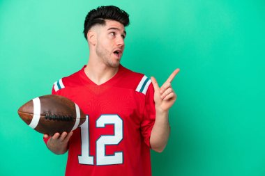 Yeşil arka planda ragbi oynayan beyaz bir genç, parmağını kaldırarak çözümü bulmaya çalışıyor.