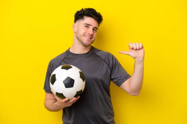 Yakışıklı genç futbolcu sarı arka planda soyutlanmış gururlu ve kendini beğenmiş.