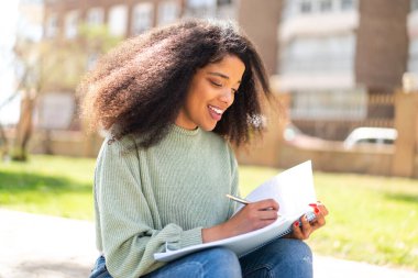 Genç Afrikalı Amerikalı bir kadın elinde bir defter tutuyor.
