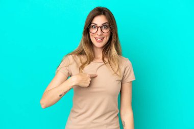 Mavi arka planda yalıtılmış beyaz bir kadın. Şaşırtıcı bir yüz ifadesi var.