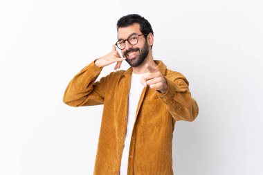Beyaz arka plan üzerinde kadife ceket giyen beyaz saçlı, sakallı yakışıklı bir adam telefon hareketleriyle ön tarafı işaret ediyor.