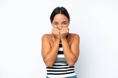 Beyaz arka planda izole edilmiş genç İspanyol kadın mutlu ve gülümsüyor elleriyle ağzını kapatıyor.