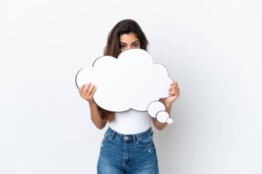 Beyaz arka planda izole edilmiş genç beyaz bir kadın düşünce balonunu tutuyor ve arkasında saklanıyor.