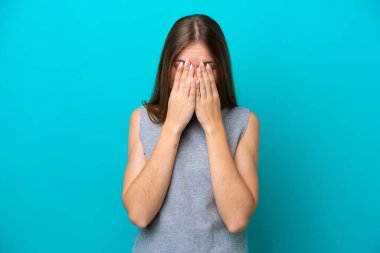 Genç Litvanyalı kadın mavi arka planda izole edilmiş, yorgun ve hasta bir ifadeyle.