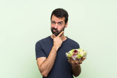 Yeşil duvarın üstünde salatalı yakışıklı bir genç.