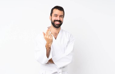 İzole edilmiş beyaz arka planda karate yapan genç bir adam davet ediyor. Gelmene sevindim.