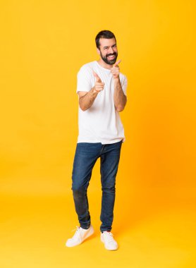 Sakallı, izole edilmiş sarı arka planda ön tarafı gösteren ve gülümseyen bir adam resmi.