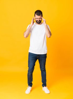 Sakallı, izole edilmiş sarı arka planda baş ağrısı olan bir adamın tam boy fotoğrafı.