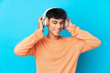 Soyutlanmış mavi arka plan müzik dinleyen genç adam.