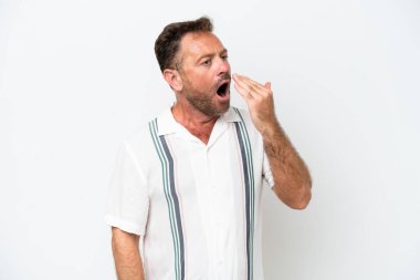 Beyaz arka planda izole edilmiş orta yaşlı beyaz bir adam esniyor ve ağzını eliyle kapatıyor.