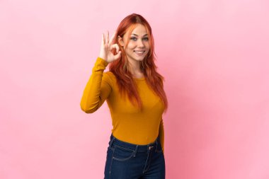 Teenager Russian girl isolated on pink background showing ok sign with fingers