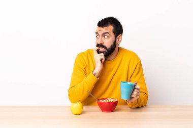 Kafkasyalı bir adam gergin ve korkmuş bir şekilde masada kahvaltı yapıyor..