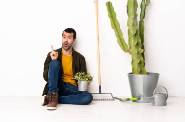 Bahçıvan içeride yerde oturuyor ve parmağını kaldırarak çözümü bulmayı umuyor.