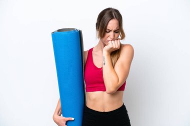 Young sport woman going to yoga classes while holding a mat isolated on white background having doubts