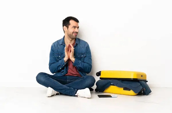 Stock image Caucasian handsome man with a suitcase full of clothes sitting on the floor at indoors scheming something