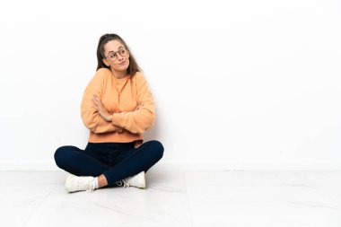 Açık kat yapma oturan genç kadın omuz kaldırma sırasında jest şüpheler