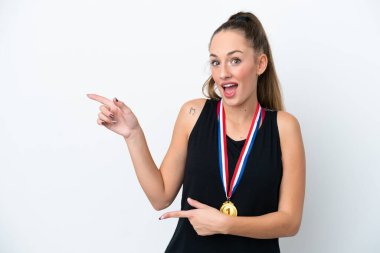 Beyaz arka planda izole edilmiş madalyalı beyaz bir kadın şaşırmış ve işaret ediyor.