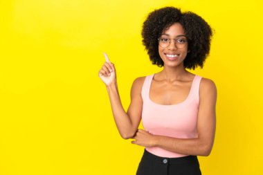 Sarı arka planda izole edilmiş genç Afrikalı Amerikalı kadın mutlu ve dik duruyor.