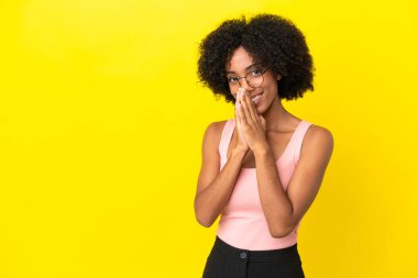 Sarı arka planda izole edilmiş genç Afrikalı Amerikalı kadın avuç içlerini bir arada tutuyor. İnsan bir şey ister.