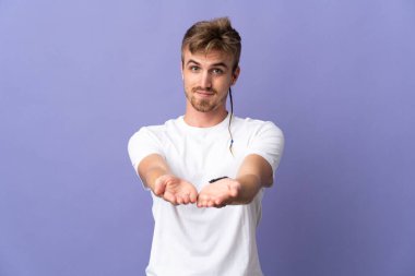 Mor arka planda izole edilmiş genç, sarışın bir adam. Avucunun içinde bir ilan vermek için hayali mekan tutuyor.