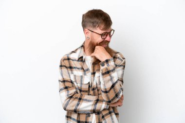 Kızıl saçlı, uzun sakallı adam beyaz arka planda izole edilmiş, yana bakıyor ve gülümsüyor.