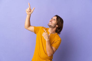 Mor arka planda izole edilmiş genç ve yakışıklı bir adam işaret parmağıyla işaret etmek harika bir fikir.