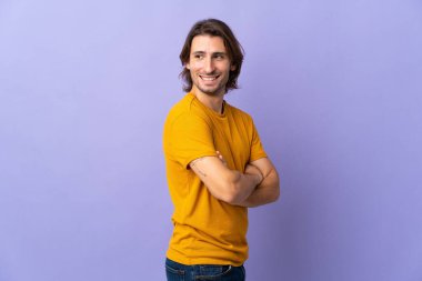 Mor arka planda soyutlanmış, kolları bağlı ve mutlu genç bir adam.