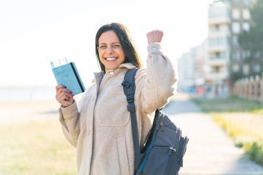 Dışarıda elinde pasaport olan genç bir kadın zaferi kutluyor.