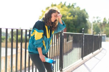 Açık havada elinde bir şişe suyla gezen genç bir bayan.