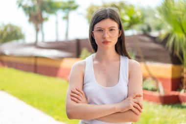 Dışarıda genç ve güzel bir kadın Gözlüğü ve kolları çaprazlanmış