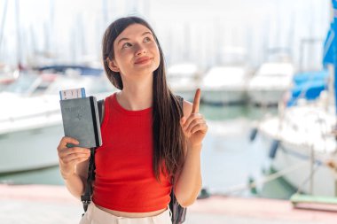 Genç, güzel Ukraynalı bir kadın elinde pasaport tutarak çözümü bulmak için parmağını kaldırıyor.