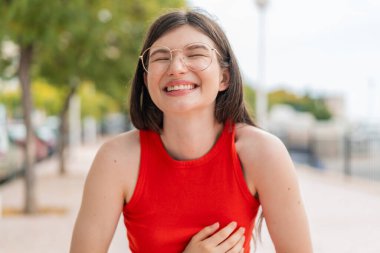 Dışarıda gözlüklü genç bir kadın gülümsüyor.