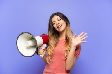 Mavi arka planda izole edilmiş genç bir Rus kızı elinde megafonla mutlu bir ifadeyle selam veriyor.