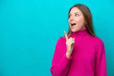 Genç Litvanyalı bir kadın mavi arka planda izole edilmiş bir şekilde parmağını kaldırarak çözümü anlamaya çalışıyor.